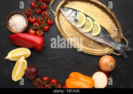 Vassoio con gustosa spigola pesce e verdure su sfondo scuro Foto Stock