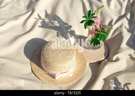 Cappelli di paglia giaceva su un bianco Coperta picnic a prato verde luminoso giorno d'estate. Foto Stock