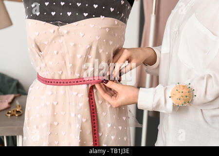 Sarto femminile prendendo le misure degli abiti sul manichino in atelier Foto Stock