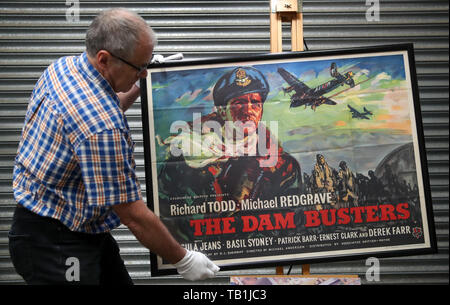 Prop Store poster consulente Mike Bloomfield regola un quad poster per il 1955 film "Dam Busters', durante una anteprima della prossima poster cinema asta al Prop Store sede vicino a Rickmansworth. Foto Stock