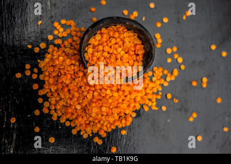 In prossimità delle materie Masur dal o masoor lenticchie o lenticchie rosa in un colorato nero ciotola di argilla su una superficie di legno. Foto Stock