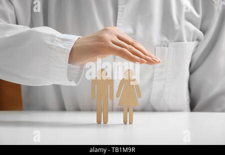 Medico donna con figure umane sul tavolo bianco, closeup. Assistenza sanitaria il concetto di assicurazione Foto Stock