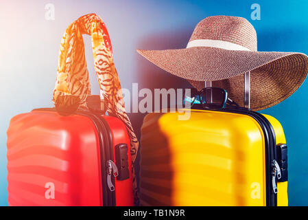 Un elegante e luminoso dimensioni cabina valigie e accessori come il concetto di vacanza contro sfondo blu scuro, copia dello spazio. Facile viaggiare con poco bagaglio Foto Stock