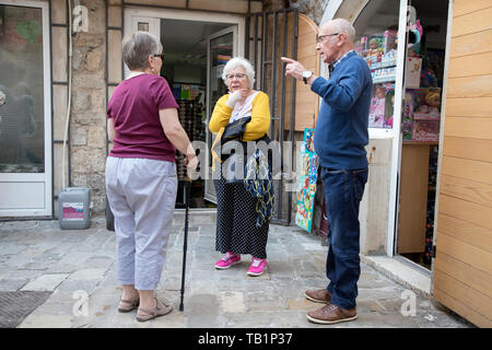 Montenegro, 2 Maggio 2019: scene di strada con tre turisti senior e permanente in chat con la città vecchia di Budva Foto Stock