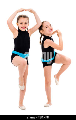 Gemello ragazze pratica e fare ginnastica ritmica, sfondo bianco. Giovane sorella ragazze sono ballare e divertirsi eseguendo gymna ritmica Foto Stock