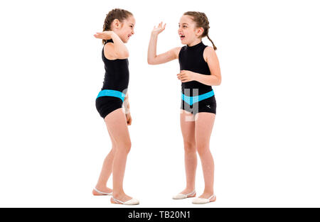 Gemello ragazze pratica e fare ginnastica ritmica, sfondo bianco. Giovane sorella ragazze sono ballare e divertirsi eseguendo gymna ritmica Foto Stock