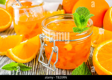 In casa orange marmellata, con freschi tagliati a fettine le arance e le foglie di menta, bianco sullo sfondo di legno spazio copia Foto Stock