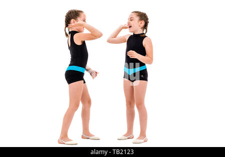 Gemello ragazze pratica e fare ginnastica ritmica, sfondo bianco. Giovane sorella ragazze sono ballare e divertirsi eseguendo gymna ritmica Foto Stock