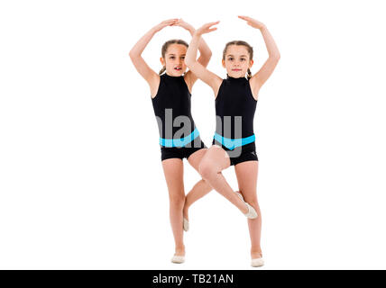 Gemello ragazze pratica e fare ginnastica ritmica, sfondo bianco. Giovane sorella ragazze sono ballare e divertirsi eseguendo gymna ritmica Foto Stock