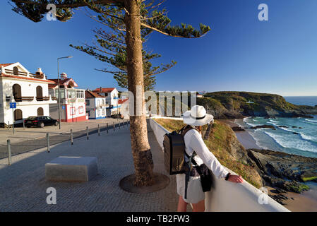 Donna con cappello e zaino cercando di wild caletta rocciosa nel villaggio di pescatori di Foto Stock