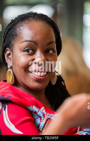 Ritratto di donna sorridente con cornrows indossare orecchini d'oro e rosso in alto. Foto Stock