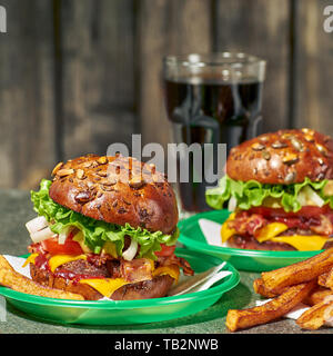 Due hamburger e bicchiere di bibita sul vecchio sfondo di legno Foto Stock