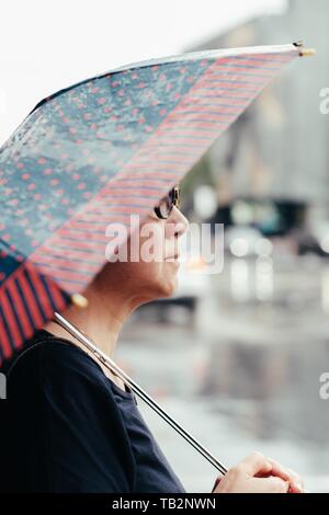 Donna asiatica anziana con ombrello Foto Stock