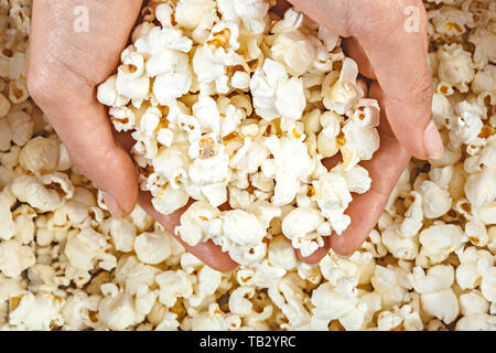 Elevato angolo di visione delle mani contengono il popcorn da una ciotola. Foto Stock