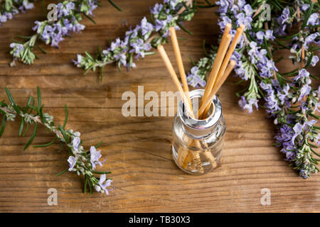 Aria di rosmarino olio rinfrescante in una bottiglia con rami di fiori Foto Stock