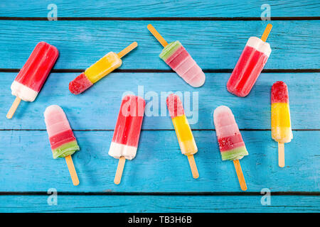 Colorata frutta gelato stick un aspetto fresco per mangiare collocato su un blu vintage in legno. Foto Stock
