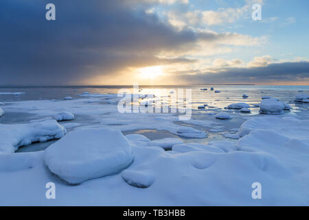 Tramonto con massi innevati e spiaggia paesaggio. Mar baltico, l'inverno. Foto Stock