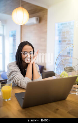 Ritratto di donna aucasian utilizzando laptop a tavola in cucina mentre interna avente la colazione a casa Foto Stock