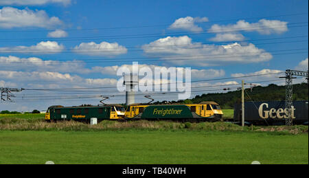 Freightliner locomotive elettriche 90016 e 90049 passare il laboratorio di ricerca water tower a Daresbury con un trasporto merci intermodale treno per la Scozia. Foto Stock