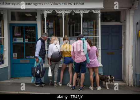 Famiglia guardando le proprietà per la vendita pubblicizzato in un agente immobiliare finestra nel West Dorset, England, Regno Unito Foto Stock