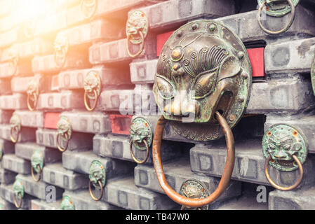 Ferro Antico Lions Head knocker porta situata su di un muro di mattoni . La Cina . Foto Stock