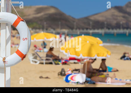 Ciambella bianco sullo sfondo della spiaggia con ombrelloni e gli ospiti su sedie a sdraio Foto Stock