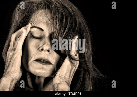 Immagine in bianco e nero di una donna matura tenendo le mani sulla testa del dolore. Foto Stock