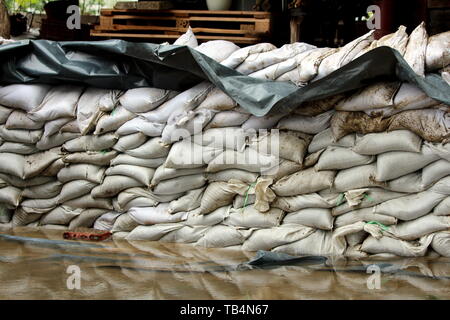 Parete temporanea fatta di sabbia bianca e di spessore in nylon nero utilizzato come protezione da alluvione per impedire allagamento dei locali case di famiglia Foto Stock