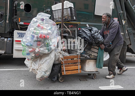 Un uomo che raccoglie il deposito vuoto bottiglie spingendo un carrello per supermercati giù Broadway a Manhattan, New York City. Foto Stock