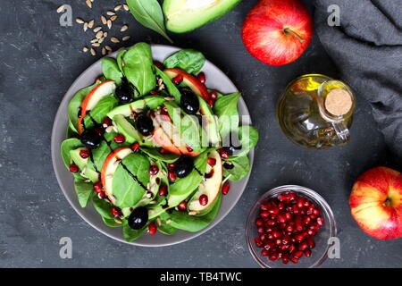 Fresca insalata di avocado con spinaci, Apple, melograno e semi di girasole su sfondo scuro. Vista da sopra con copia spazio. Foto Stock