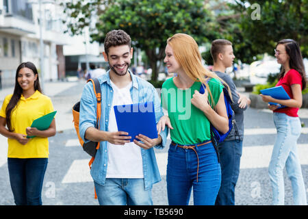 Inglese per studenti di sesso femminile e spagnolo ragazzo con gruppo di studenti mutliethnic outdoor in città in estate Foto Stock
