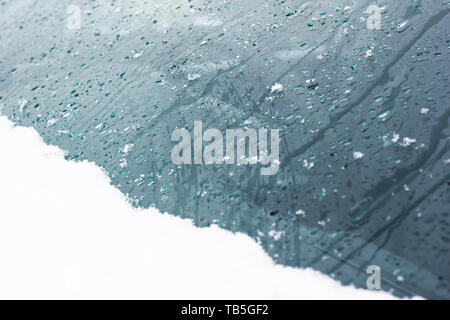 La neve e le gocce di pioggia sul vetro come sfondo. Foto Stock