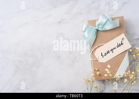 Evento design concept - vista superiore dei padri di layout di giorno con la scrittura la calligrafia, kraft confezione regalo e fiore giallo su marmo bianco di sfondo, copia Foto Stock