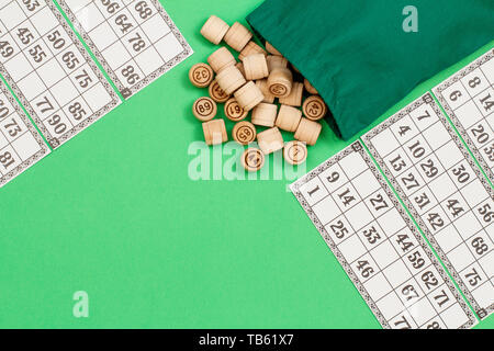 Lotto in legno Barili con borsa di stoffa e carte da gioco su sfondo verde. Gioco di bordo del lotto. Vista da sopra con copia spazio. Foto Stock