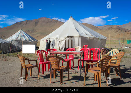 Una piccola fortuna tenda temporanea ristorante in un deserto in Ladakh. Sedie di plastica e la tabella mantenuta al di fuori della tenda Foto Stock