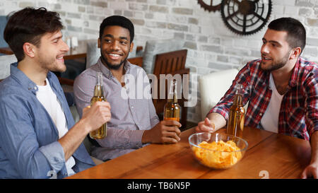 Gli uomini in appoggio in bar e mangiare patatine e bere birra, Condivisione Ultime Notizie Foto Stock