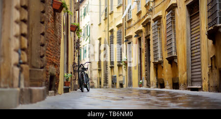 Le biciclette parcheggiate su belle strade medievali della città di Lucca, noto per la sua intatta mura rinascimentali della città, Toscana, Italia. Foto Stock