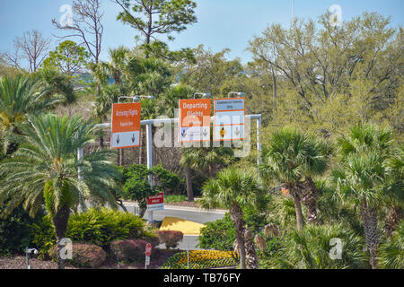 Orlando, Florida. Marzo 01, 2019. I voli in partenza e in arrivo i segni sulla foresta verde background all'Aeroporto Internazionale di Orlando. Foto Stock