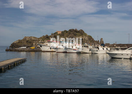 Aci Trezza Siciy, porto turistico con battelli turistici e barche da pesca, l'isola rocciosa in background Foto Stock