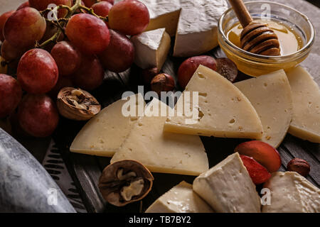 Assortimento di formaggi saporiti con miele e uva a bordo Foto Stock