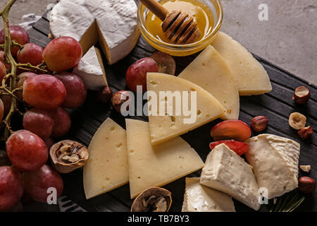 Assortimento di formaggi saporiti con miele e uva a bordo Foto Stock