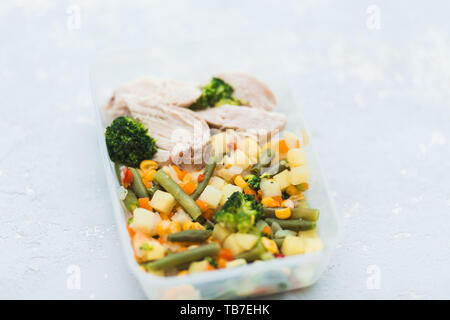 Delizioso e sano il pranzo. Carne di pollo con verdure bollite nel contenitore su sfondo grigio. Pulire sano concetto alimentare, vicino. Foto Stock