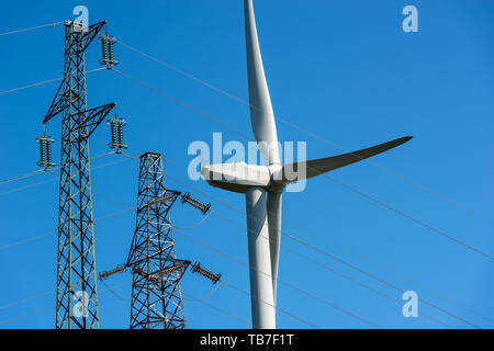 Turbina eolica e alte torri di tensione (power line) su un cielo blu chiaro - Energie rinnovabili concetto Foto Stock