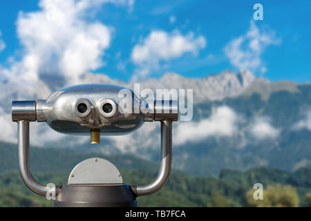 A gettone binocolo elettronico per i turisti su una offuscata paesaggio di montagna Foto Stock