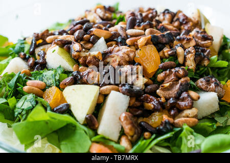 Dado di pino con insalata di noce, pera, albicocca secca, rucola o foglie di rucola in recipiente di vetro. Alimenti biologici. Foto Stock