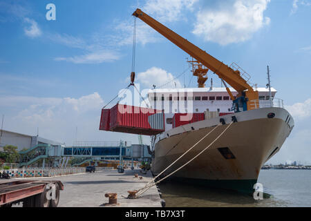 Dei portuali scaricare container da una nave mentre è inserito in Indonesia Foto Stock