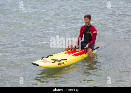 Bournemouth, Dorset, Regno Unito. 31 maggio 2019. Tempo in Gran Bretagna: nuvoloso e arioso a Bournemouth spiagge, come le temperature sono previste per aumentare per il fine settimana. RNLI Lifeguard seduto sul surf board in mare. Credit: Carolyn Jenkins/Alamy Live News Foto Stock