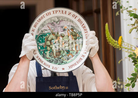 Londra, Regno Unito. Il 31 maggio 2019. Un tecnico presenta 'prodezze del lavoro', un sovietico piatto porcellana realizzati nello Stato fabbrica di porcellana, circa 1921 (Est. GBP 30,000-50,000) in corrispondenza di un'anteprima delle opere dalla prossima vendita di russo foto, opere d'arte, Fabergé & Vendite icone da Sotheby's New Bond Street, il 4 giugno 2019. Credito: Stephen Chung / Alamy Live News Foto Stock