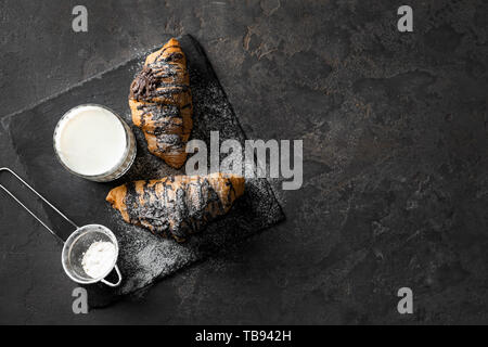 Croissant saporiti con un bicchiere di latte su sfondo grigio Foto Stock