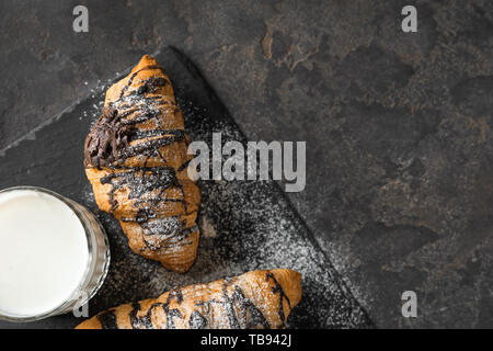 Croissant saporiti con un bicchiere di latte su sfondo grigio Foto Stock